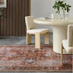 Rug placed under round dining table and cream upholstered chairs in modern dining room