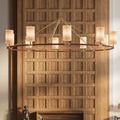 Chandelier with tan linen shades in ambient light, positioned in front of paneled wood wall