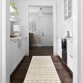 Rivi rug shown laid in bright kitchen with white cabinets and dark wood floor, highlighting rug’s runner size and room pla...