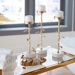 Top shelf of bar cart styled with gold candle holders, rolled white towels, and decorative gold accents