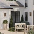 View of outdoor patio with antique brass Royster sconces on white brick walls surrounded by plants and outdoor furniture