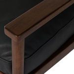 Close-up of warm wood armrest and black leather cushion detail