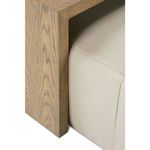 Close view of side table wooden frame with visible wood grain over ottoman cushion edge