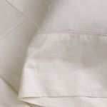 Close-up of hemstitch border detail on ivory cotton sateen sheet fabric