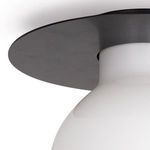 Angled close-up of the edge of the matte black circular base and upper portion of the white shade