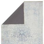 Back side of rug reveals dark gray backing contrasting with the blue and white front medallion design