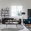 Sofa styled in bright living room with striped rug, modern coffee table, and teal velvet armchairs
