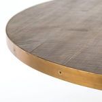 Close-up from above of rounded table edge with burnt oak wood grain framed by brass steel band