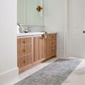 Darling Olive rug used as bathroom runner alongside wood vanity and white marble tile flooring