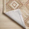 Corner of Varena rug flipped over showing branded fabric backing and hand-tufted edge