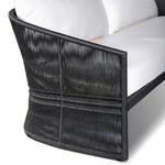 Close-up of sofa arm corner showing woven black rope around frame and white seat cushion