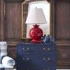 Red ceramic lamp styled on navy dresser in a cozy room with mirror and wooden paneled wall