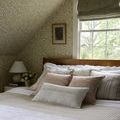Harvey white pillow styled on bed with neutral patterned bedding and green leafy wallpaper background