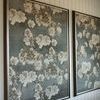 Angle view of two Drifting Blooms II paintings mounted side by side on white paneled wall with ceiling beam above
