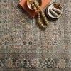 Close overhead view of rug with decorative beads and small plates on top