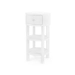 Round cream-colored side table with one drawer, two open shelves, brass pull and sabots on legs