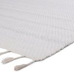 Close-up of rug corner showing woven texture and white tassels on edges