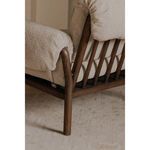 Close-up rear angle showing spindle back and angled wooden frame leg on textured rug