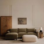 Living room scene with Marion Square Ottoman centered before green sectional, wood cabinet, and wall art