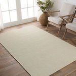 Cream ribbed wool rug styled on wood flooring next to light wood frame armchair and window
