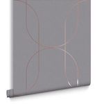 Rolled wallpaper with detailed view of rose gold curves and textured gray surface