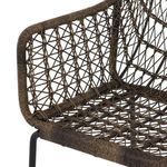 Side angle showing chair front leg and metal footrest under woven armrest