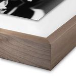 Close-up detail of light wood frame corner and white mat surrounding black and white photo