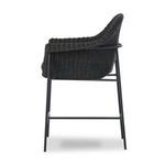 Three-quarter front view emphasizing rounded wicker arms and sturdy iron frame