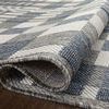Close-up of the rug partially rolled, revealing textured polypropylene pile and backing