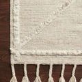Close-up corner view displaying diagonal textured patterns and twisted fringe on wooden floor