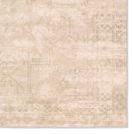 Close crop of corner showing faded medallion design and worn edges in soft tan and cream colors
