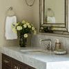 Enveloped Glass Vase with yellow flowers placed on marble bathroom countertop near mirror and towel holder