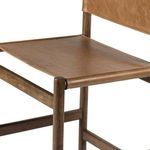 Close-up of the front right corner showing leather seat tightly stretched and rounded wooden leg