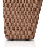 Curved light brown wicker armrest framing the white cushion of the outdoor chair