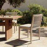 Outdoor setting with Sherwood Washed Brown Outdoor Dining Chair beside wooden table under tree shade