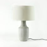 Lamp switched on with visible power cord on clean white background, showing tall silhouette.