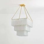Unlit chandelier highlighting cool, milky alabaster panels and warm brass finials against white wall
