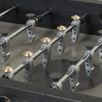 Foosball rods with both metallic bronze and black detailed players on the concrete playing surface