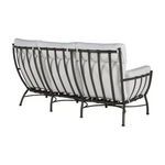 Angled rear side view of sofa exposing white cushions and metal frame structure