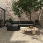 Miles outdoor sofa in outdoor courtyard setting with stone floor, tree, and cream stone coffee table