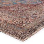 Close-up on corner showing stitched edge and detailed floral medallion pattern with blue and rust tones
