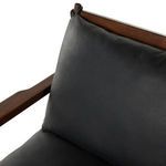 Close detail of leather tie securing cushion to rounded wood arm post