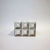 Front view highlighting square face with raised cube bone details and textured beige background