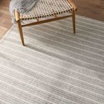 Top-down view of rug under chair legs highlighting striped pattern and texture in indoor setting