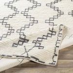 Corner of Beni Ourain wool rug lifted to reveal thickness and woven underside detail