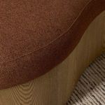 Side angle detail of seat and base seam showing fabric contour and wood grain curves on carpet
