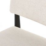 Close-up of fabric upholstery next to black wooden chair back support