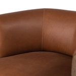 Side rear perspective highlighting rounded leather back and dark wood legs