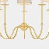 Close-up of the aged brass finish on the chandelier’s bobeches and the swooping J-arms