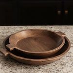 Set of two wooden bowls stacked on granite countertop with dark background, showing curved wood grain in warm lighting